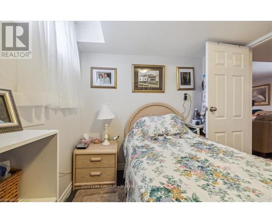 A bedroom with a floral bedspread and a white bedside table with a lamp on it.