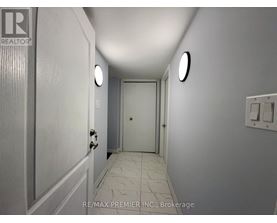 A hallway with a door at the end and a light switch on the wall.