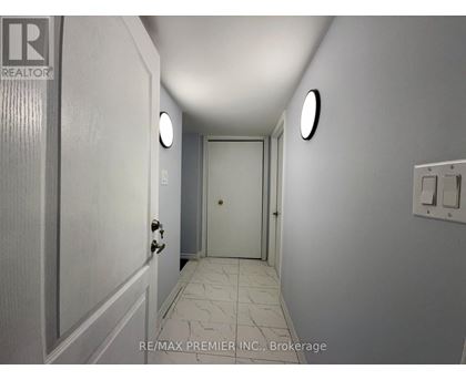 A hallway with a door at the end and a light switch on the wall.