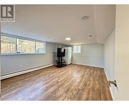A spacious room with wooden flooring and a flat-screen TV.