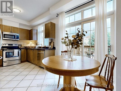 A kitchen with a table and chairs in the foreground and a balcony with a table and chairs in the background.