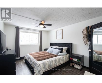 A bedroom with a bed, a ceiling fan, and a window with curtains.
