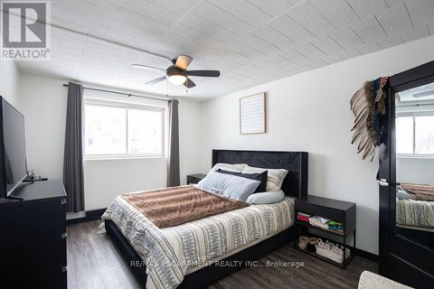A bedroom with a bed, a ceiling fan, and a window with curtains.