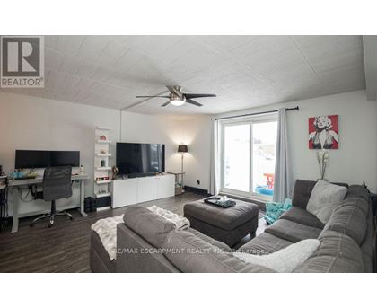 A living room with a grey couch and a white ceiling fan.