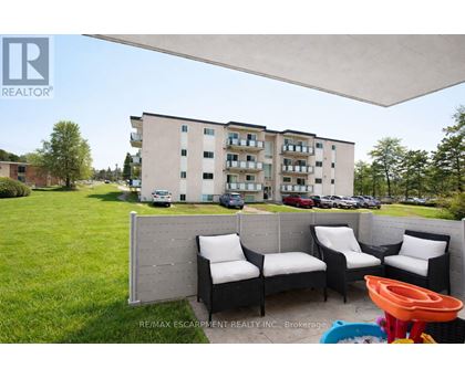 A patio with a white couch and chairs is in front of a building.