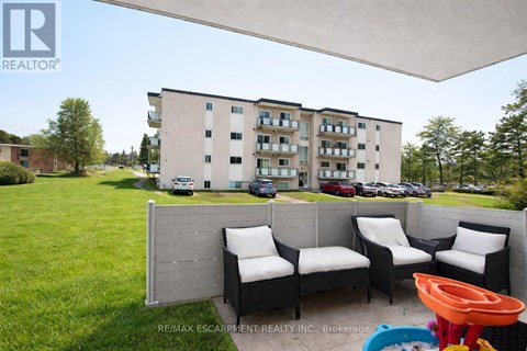 A patio with a white couch and chairs is in front of a building.