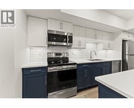 A kitchen with white and blue cabinets and appliances.