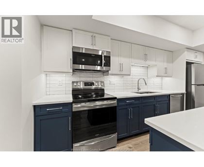 A kitchen with white and blue cabinets and appliances.