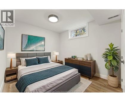 A bedroom with a bed, nightstands, and a plant.