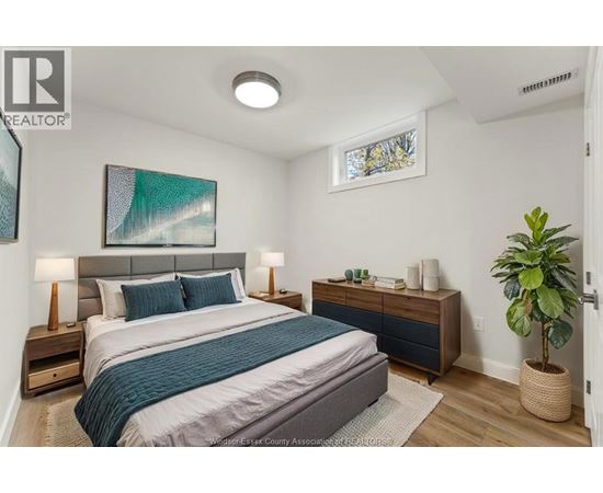 A bedroom with a bed, nightstands, and a plant.