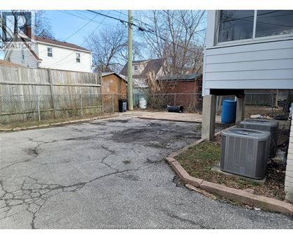 A driveway with a cracked surface leads to a house.