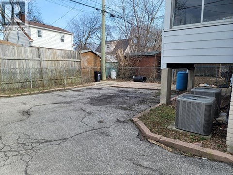 A driveway with a cracked surface leads to a house.