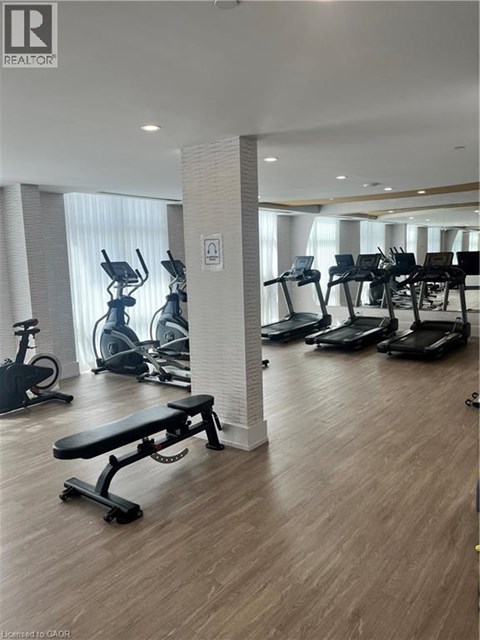 A gym with a variety of equipment including treadmills, stationary bikes, and a bench.