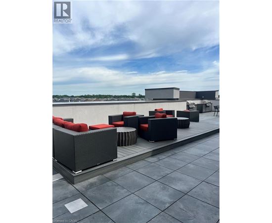 A rooftop patio with black furniture and a cloudy sky.