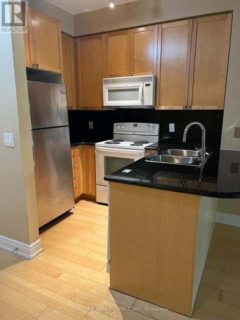 A kitchen with wooden cabinets and a black counter top.