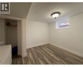 A room with wood flooring and a window with a view of trees outside.