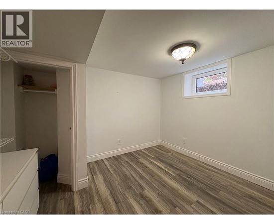 A room with wood flooring and a window with a view of trees outside.