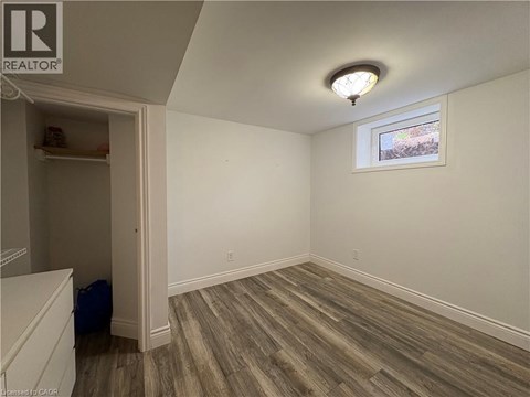 A room with wood flooring and a window with a view of trees outside.