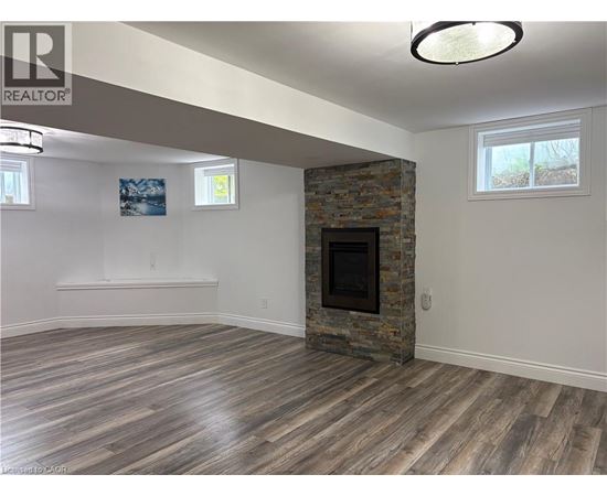 A living room with a stone fireplace and wood flooring.