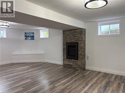 A living room with a stone fireplace and wood flooring.