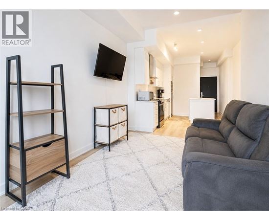 A living room with a grey couch and a flat screen TV mounted on the wall.