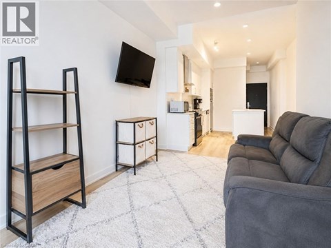 A living room with a grey couch and a flat screen TV mounted on the wall.