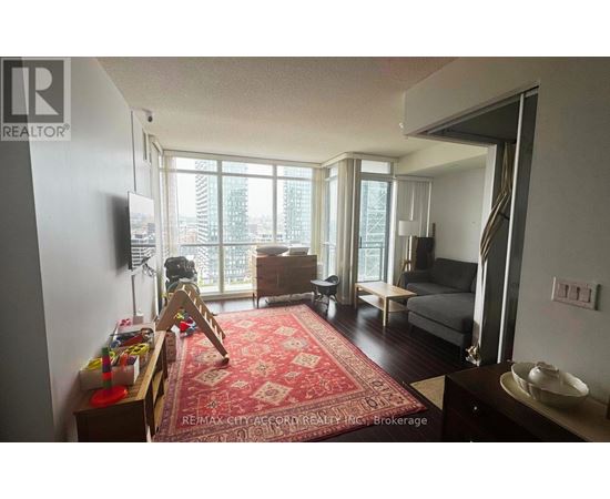 A living room with a red rug and a television.
