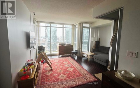 A living room with a red rug and a television.
