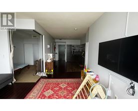 A living room with a rug on the floor and a television on the wall.