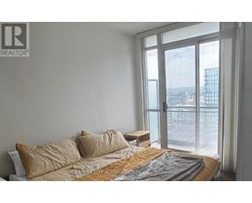 A bedroom with a large bed and a view of the city outside the window.