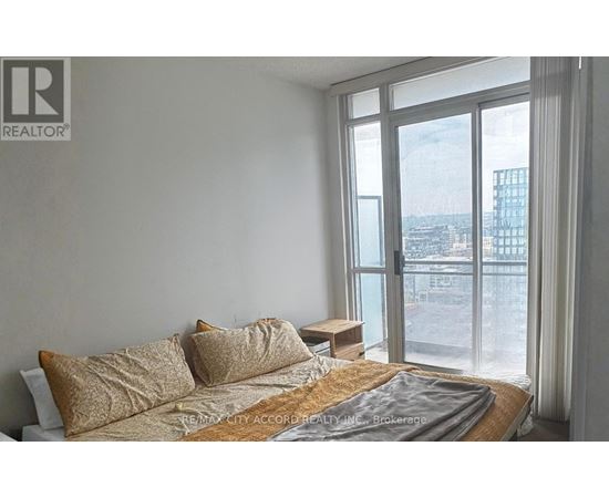 A bedroom with a large bed and a view of the city outside the window.