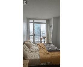 A bedroom with a bed and a window overlooking a cityscape.