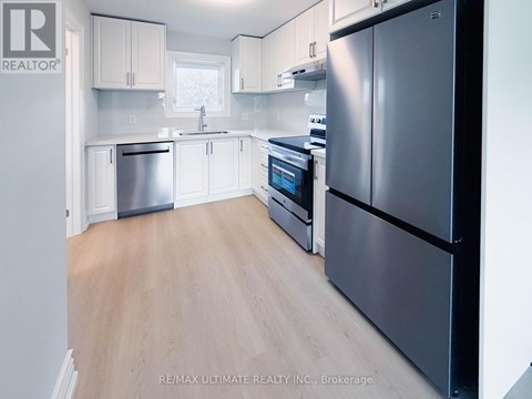 A kitchen with a black refrigerator, white cabinets, and a wooden floor.