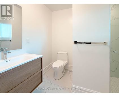 A white toilet in a bathroom with a sink and a towel bar.