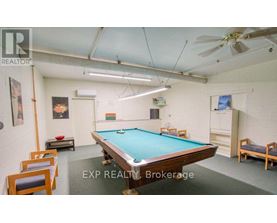 A pool table is surrounded by chairs in a room with a ceiling fan.