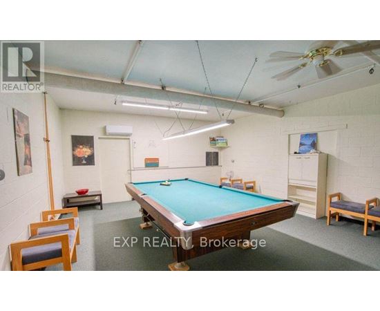 A pool table is surrounded by chairs in a room with a ceiling fan.