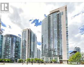 A tall building with a glass facade stands in front of other buildings.