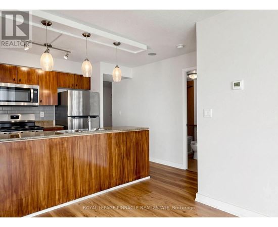A modern kitchen with wooden cabinets and a stainless steel refrigerator.