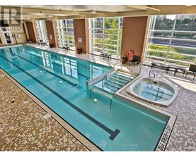 A large indoor swimming pool with a hot tub and a view of the outdoors.