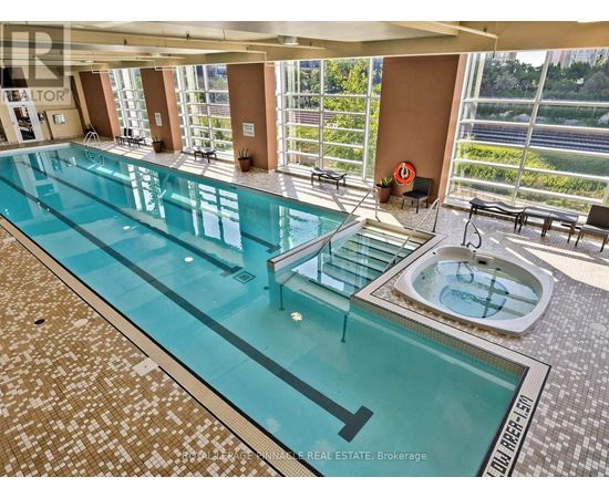 A large indoor swimming pool with a hot tub and a view of the outdoors.