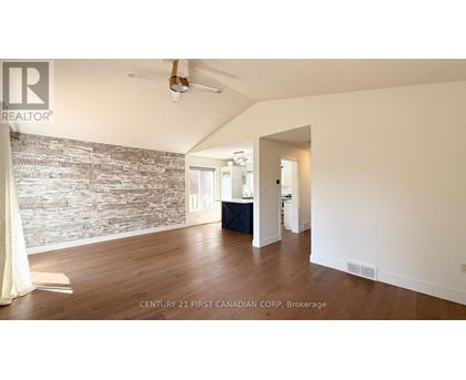 A spacious room with a wooden floor and a stone wall.