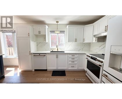 A white kitchen with a black mat on the floor.