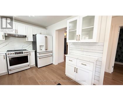 A kitchen with white cabinets and a wooden floor.