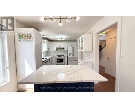 A kitchen with a marble countertop and a logo on the fridge.