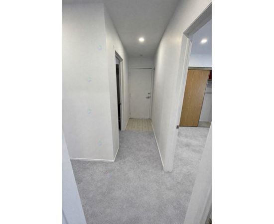 A long, narrow hallway with white walls and carpeted floor.
