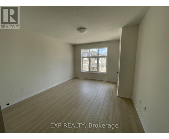 A room with wooden flooring and a window with a view of a building outside.