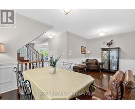 A dining room with a table set for two and a couch.