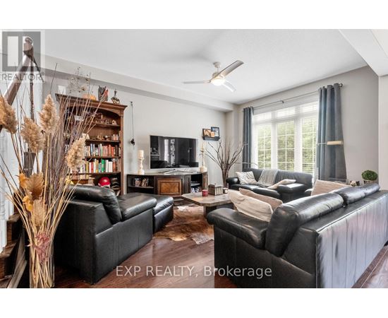 A living room with black leather sofas and a wooden floor.
