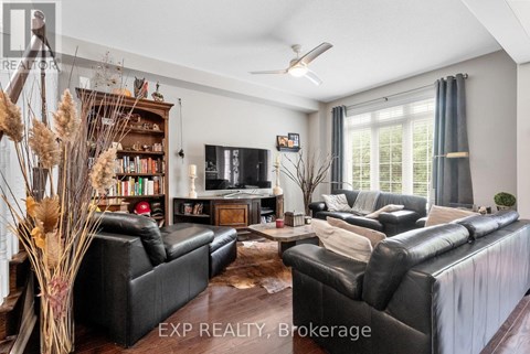 A living room with black leather sofas and a wooden floor.