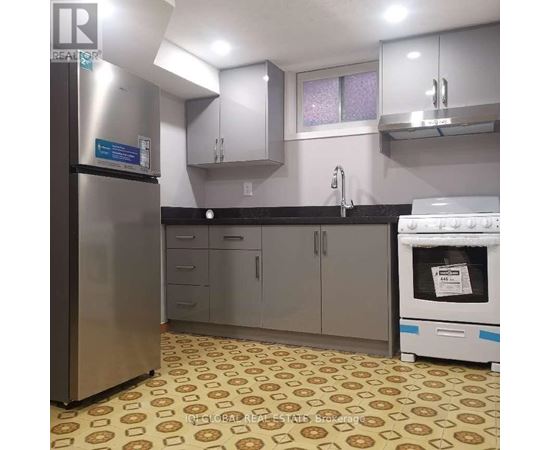 A kitchen with a refrigerator, oven, and cabinets.